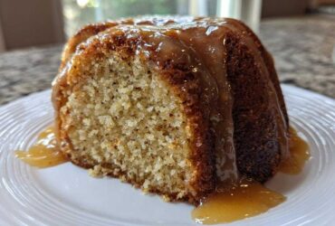 Close-up of a slice of moist bacardi rum cake topped with a thick, dripping rum glaze on a white plate.