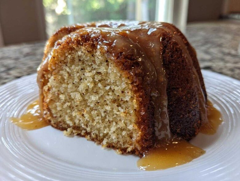 Close-up of a slice of moist bacardi rum cake topped with a thick, dripping rum glaze on a white plate.