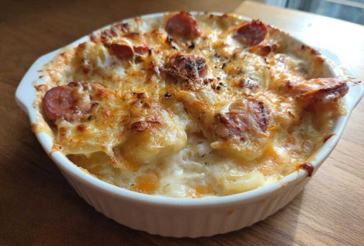 A bubbling, golden-brown baked pierogi casserole topped with melted cheese and sliced sausage.