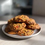 A tempting stack of freshly baked fruitcake cookies featuring colorful candied fruit pieces, resting on a white plate.