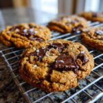 Close-up of freshly baked brown butter chocolate chip cookies sprinkled with sea salt on a cooling rack.