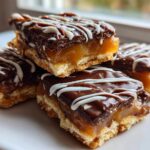 A stack of rich caramel ritz cracker christmas cookies topped with chocolate ganache and white icing drizzle.