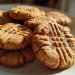 A stack of freshly baked, chewy peanut butter cookies featuring classic crosshatch fork marks and sprinkled with sugar.