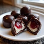 Two halves of a chocolate covered cherries showing the white coconut filling and bright red cherry center.