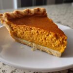 A close-up of one perfect slice of classic pumpkin pie recipe on a white plate.