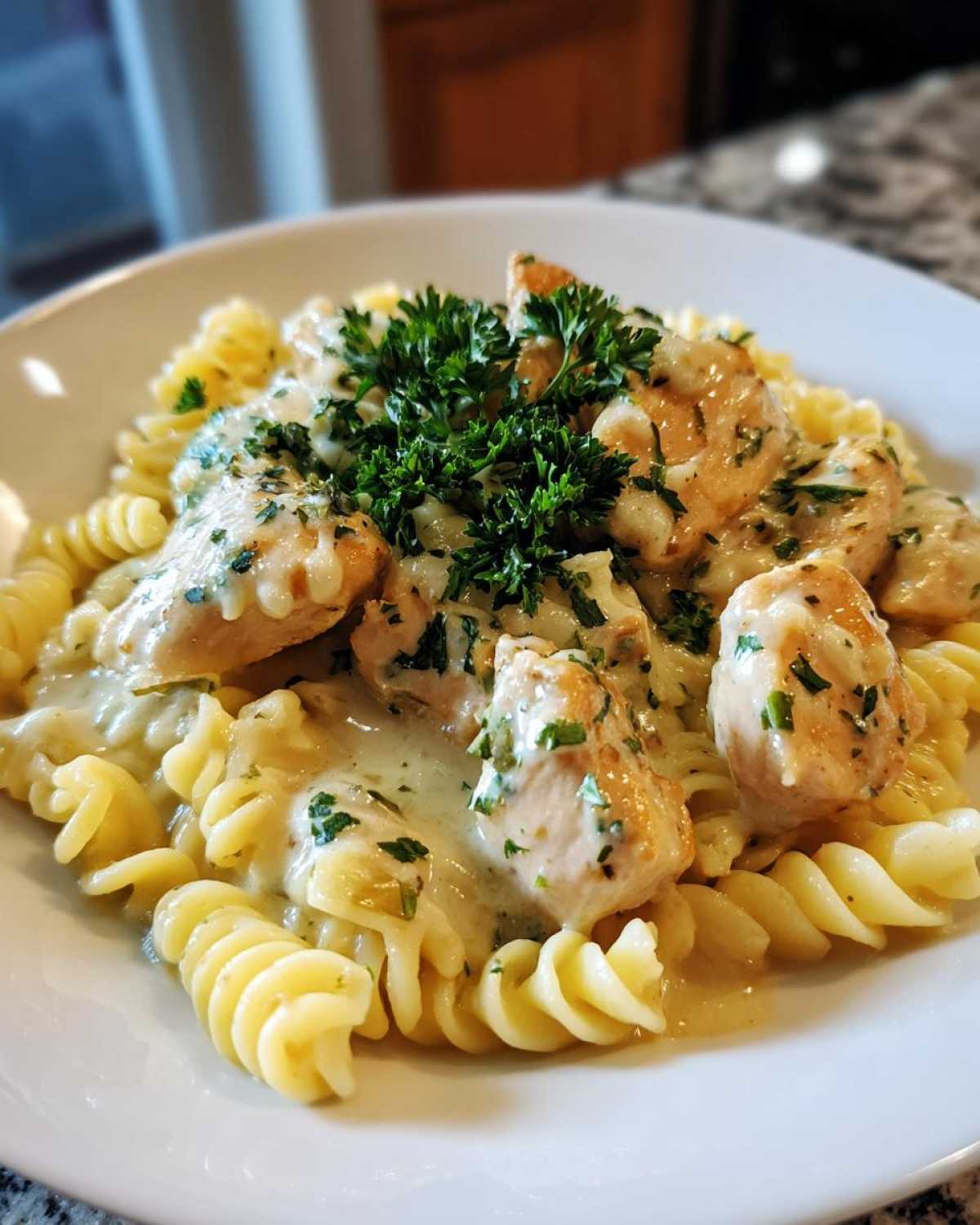 Close-up of creamy chicken pasta featuring fusilli noodles, tender chicken pieces, and a fresh parsley topping.