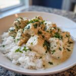 Close-up of creamy coconut lime chicken pieces served over fluffy white rice and garnished with fresh parsley.
