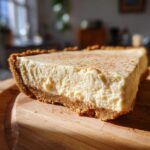 A thick slice of creamy, no-bake eggnog pie with a graham cracker crust, dusted with cinnamon.