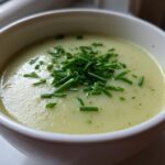 Close-up of a bowl of creamy leek soup, garnished generously with freshly chopped green chives.