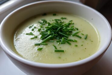 Close-up of a bowl of creamy leek soup, garnished generously with freshly chopped green chives.