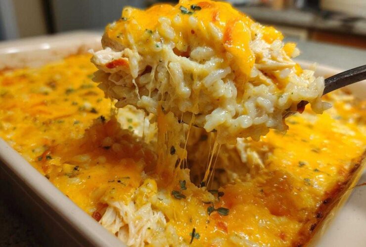 A spoonful of creamy rice casserole being lifted, showing melted cheese strings stretching back to the dish.