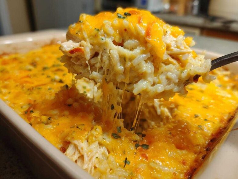 A spoonful of creamy rice casserole being lifted, showing melted cheese strings stretching back to the dish.