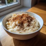 A white bowl filled with creamy rice pudding recipe, generously dusted with cinnamon powder.