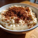 Close-up of a bowl of creamy rice pudding recipe generously dusted with ground cinnamon.