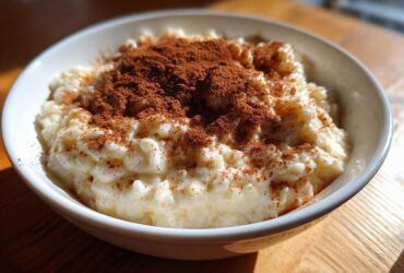 Close-up of a bowl of creamy rice pudding recipe generously dusted with ground cinnamon.