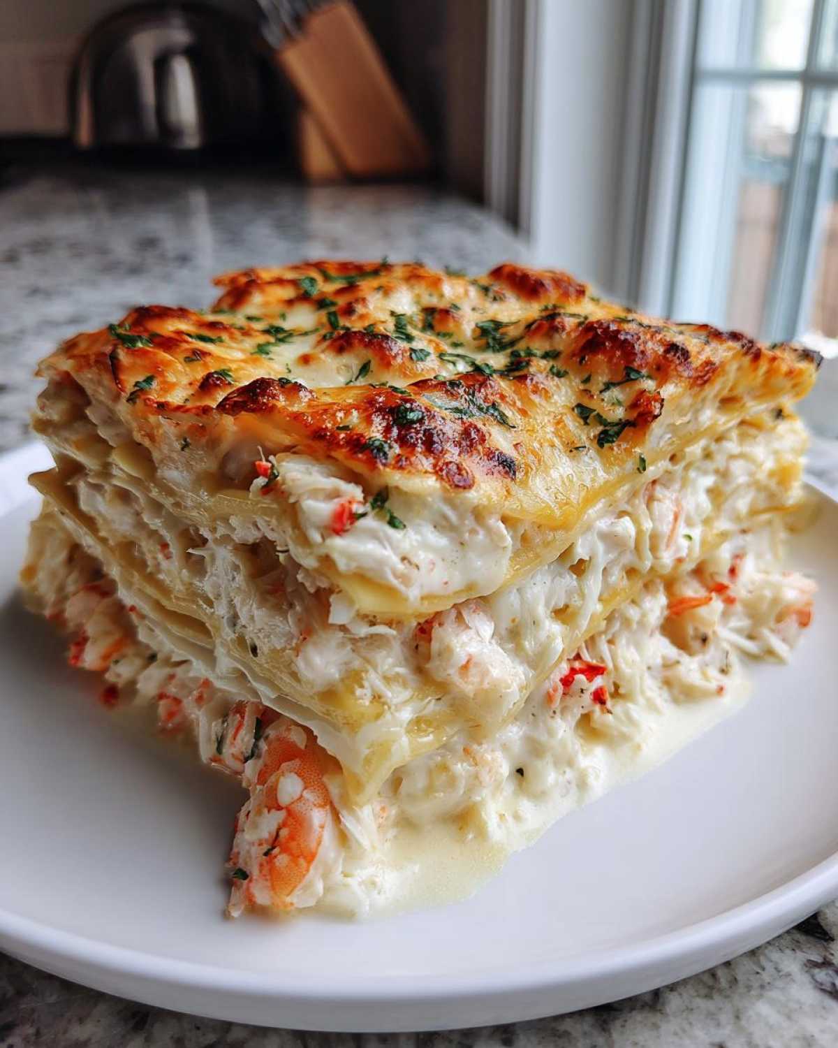 A tall, layered slice of creamy seafood lasagna featuring shrimp and crab in a white sauce, topped with melted, browned cheese and parsley.