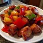 Close-up of glazed chicken pieces mixed with pineapple chunks and colorful bell peppers from the hawaiian chicken sheet pan.