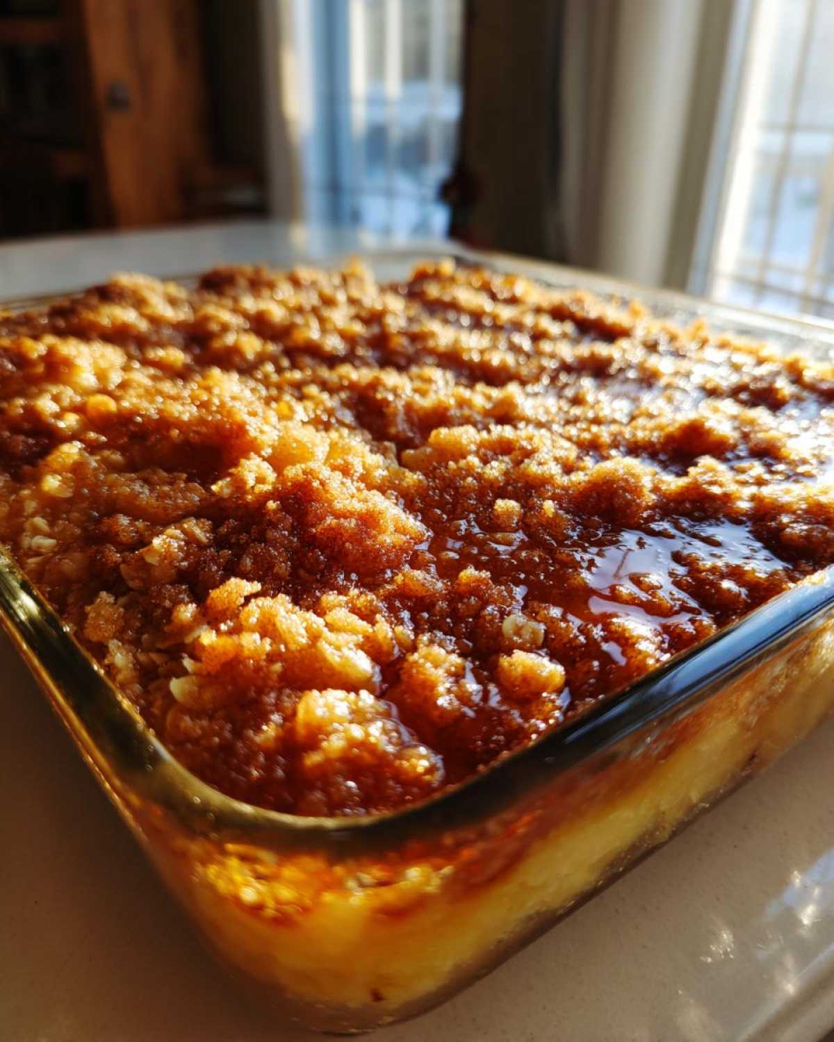 Close-up of a freshly baked apple crisp recipe in a glass dish, showing a bubbling, golden-brown, crumbly topping.