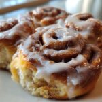 Close-up of three freshly baked, gooey cinnamon roll bites topped with thick white icing.