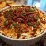A freshly baked, cheesy popper dip topped with crispy bacon bits and green onions.
