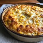 Close-up of baked mexican street corn dip bubbling with melted, browned cheese and visible corn kernels in a ceramic dish.