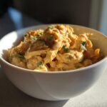 Close-up of creamy, shredded chicken and beans in a white bowl, representing instant pot white chicken chili.