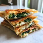 Stack of four golden-brown Mediterranean Spinach and Feta Cheese Crisps cut in half, showing the filling.