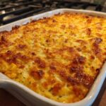 Close-up of a bubbling, golden-brown baked mexican street corn dip in a white rectangular baking dish.