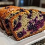Close-up of moist blueberry banana bread slices showing a dense crumb packed with juicy, burst blueberries.