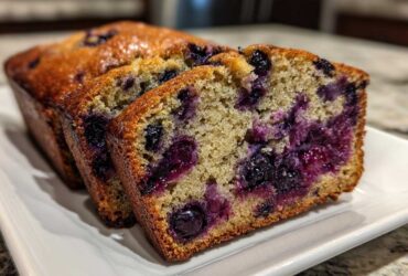 Close-up of moist blueberry banana bread slices showing a dense crumb packed with juicy, burst blueberries.