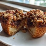 A pecan pie muffin cut in half, revealing a gooey brown sugar filling and a crunchy streusel topping.