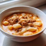 Close-up of a hearty bowl of creamy sausage gnocchi soup, featuring soft gnocchi and browned sausage.