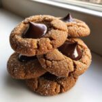 A stack of four sugary peanut butter blossom cookies topped with melted chocolate kisses.