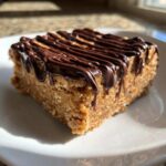 Close-up of a single, thick, no-bake protein bars square topped with drizzled dark chocolate.
