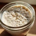 Overhead view of a very active sourdough starter, showing a thick layer of foam and bubbles on top.