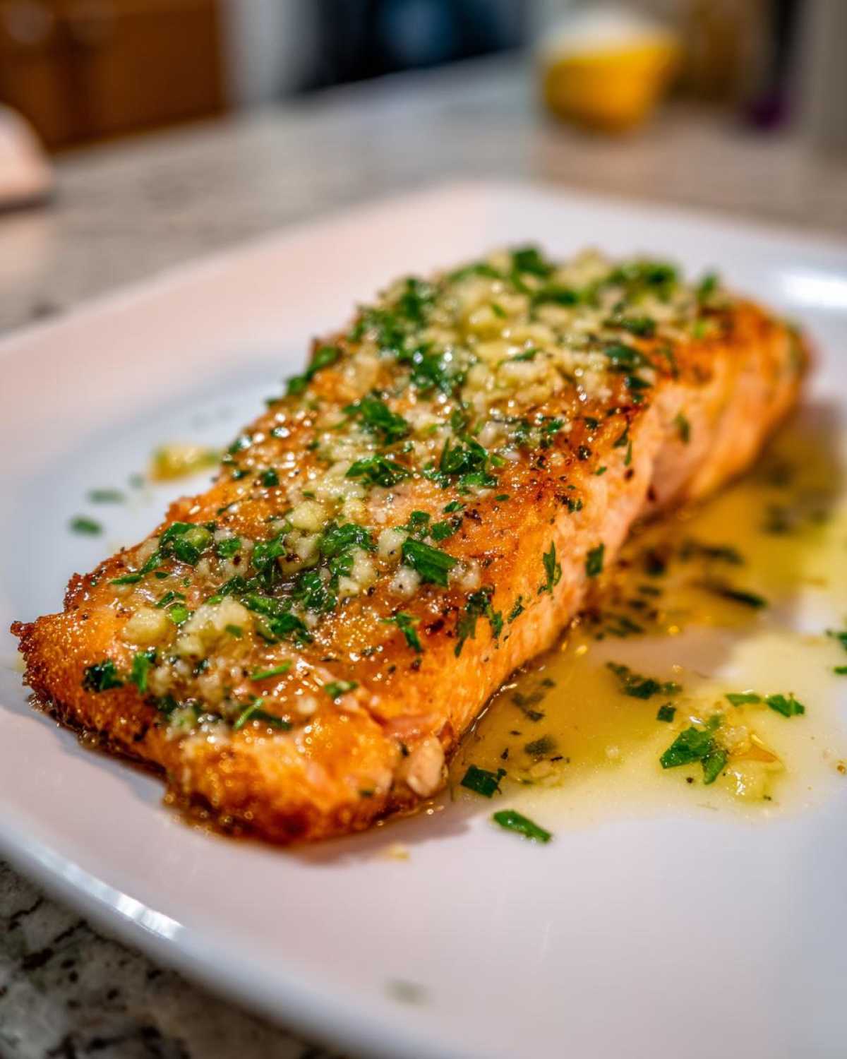 Close-up of a perfectly cooked air fryer salmon fillet topped with melted garlic butter and fresh parsley.