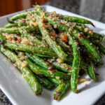 A close-up of bright green beans roasted and topped with crunchy breadcrumbs and salt.