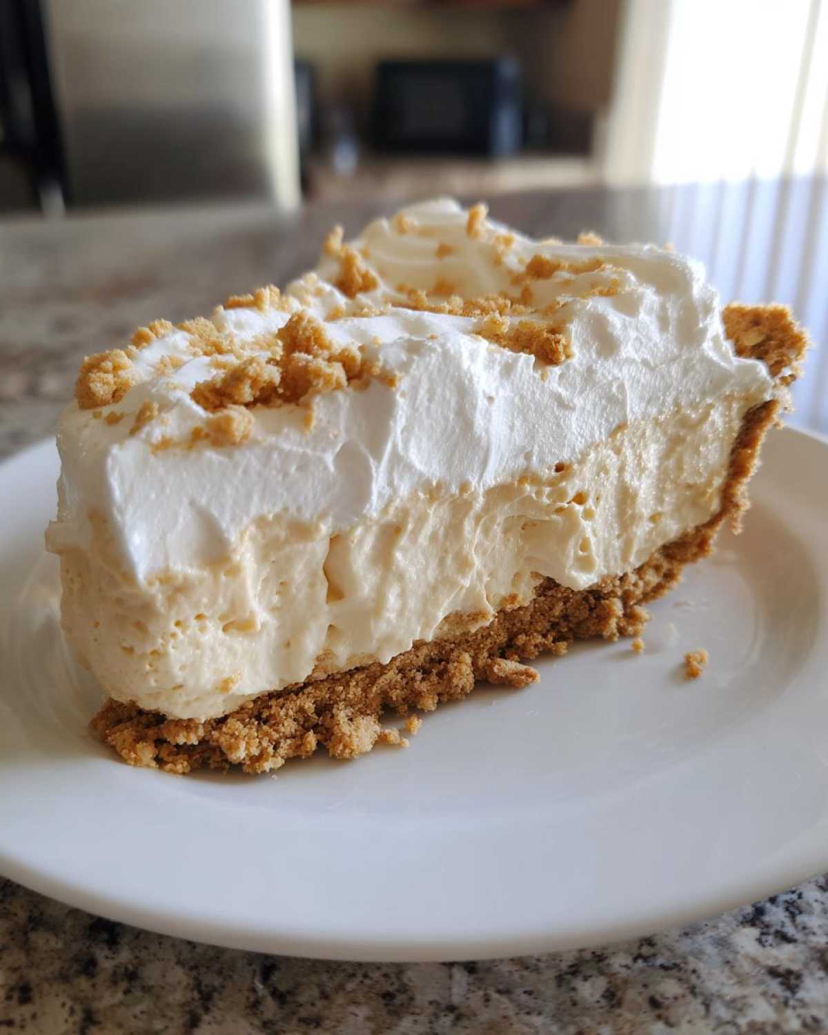 A thick slice of creamy peanut butter pie with a graham cracker crust and whipped topping.