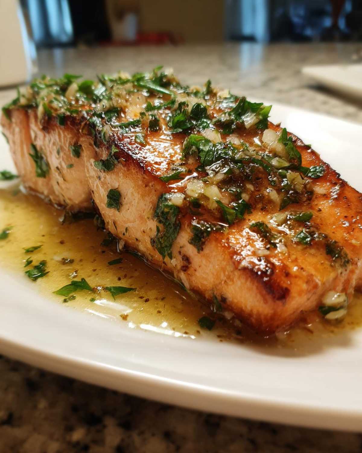 Close-up of a juicy air fryer salmon fillet topped with melted garlic butter and fresh parsley.