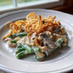 A close-up serving of amazing green bean casserole topped generously with crispy fried onions.