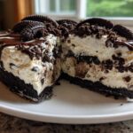 A cross-section of a decadent ice cream pie showing a dark cookie crust, creamy filling with cookie chunks, and chocolate drizzle.