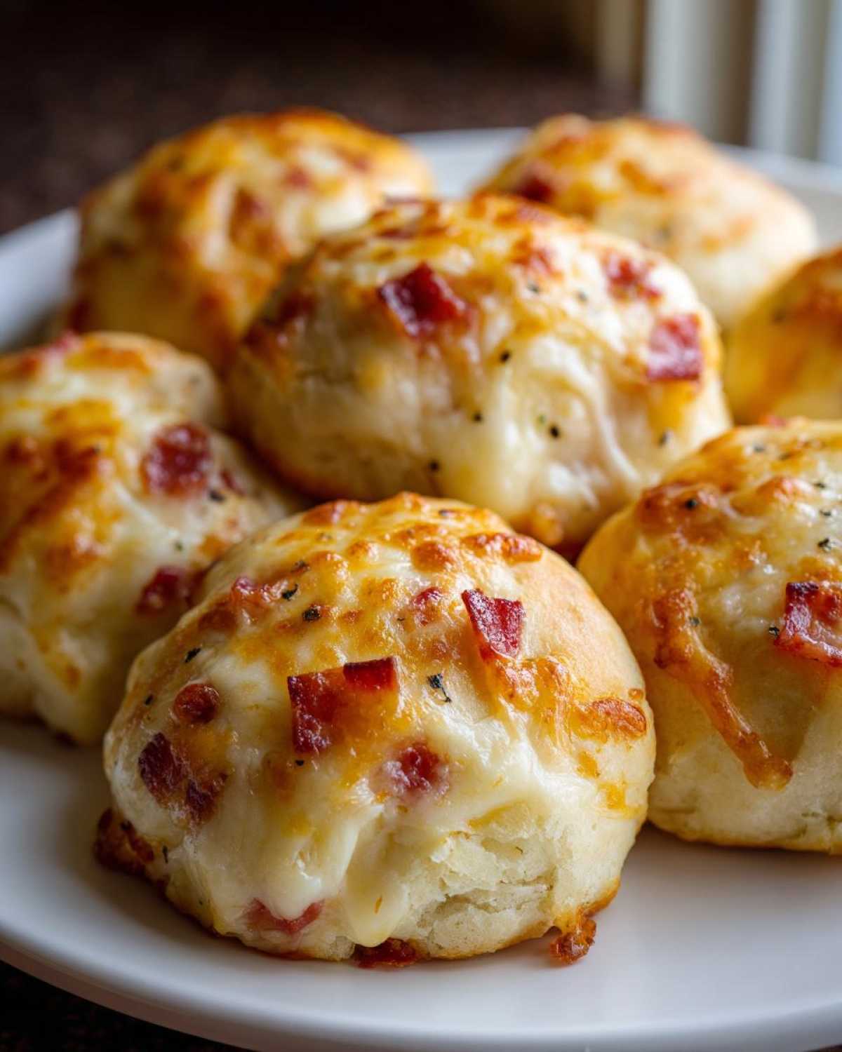Close-up of several golden brown pizza bites topped with melted cheese and small pieces of pepperoni.