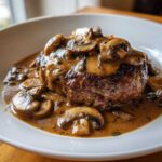 Close-up of a perfectly cooked Salisbury steak smothered in rich, creamy mushroom gravy.
