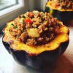 A close-up of a perfectly baked stuffed acorn squash half filled with savory quinoa, meat, and vegetables.