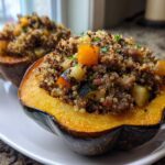 Two halves of baked stuffed acorn squash filled with a mixture of quinoa, ground meat, and diced vegetables.