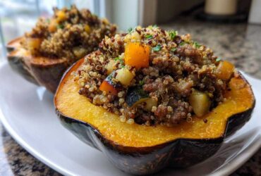 Two halves of baked stuffed acorn squash filled with a mixture of quinoa, ground meat, and diced vegetables.