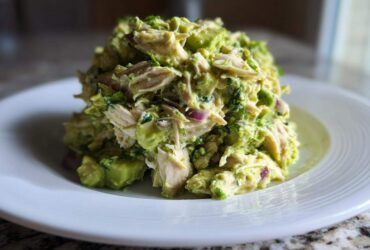 A generous mound of creamy avocado chicken salad served on a white plate.