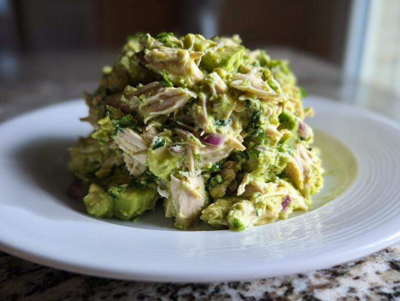 A generous mound of creamy avocado chicken salad served on a white plate.