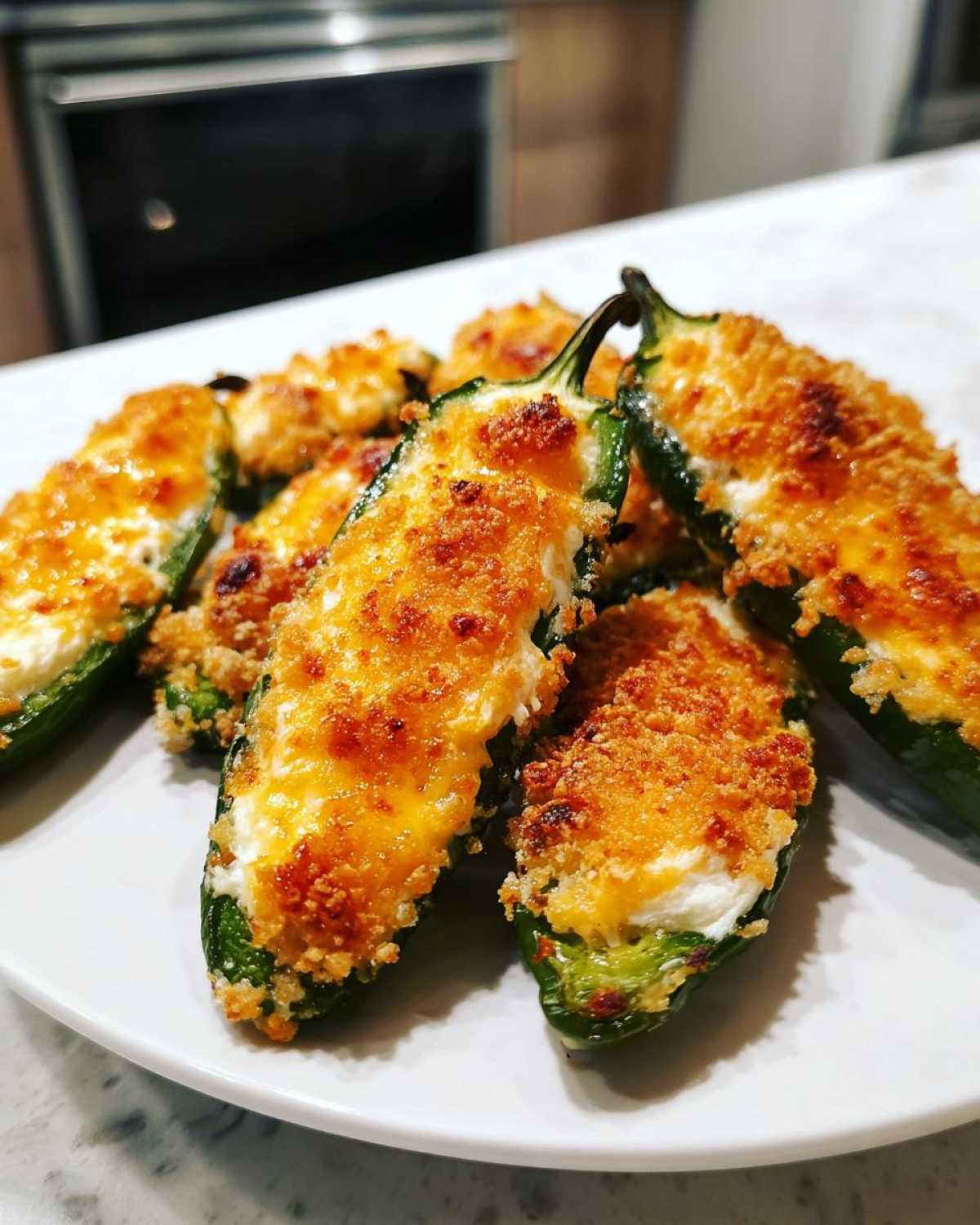 Close-up of several golden-brown baked jalapeño poppers filled with cheese and topped with crispy breadcrumbs.