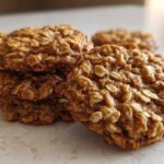 Close-up of a small stack of golden brown banana oatmeal cookies featuring visible rolled oats.